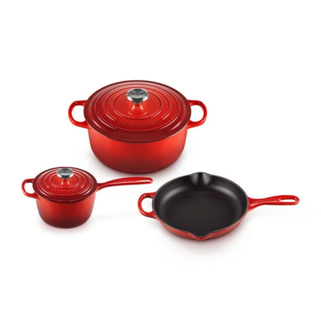 Set of three red cookware items including a Dutch oven a saucepan and a skillet