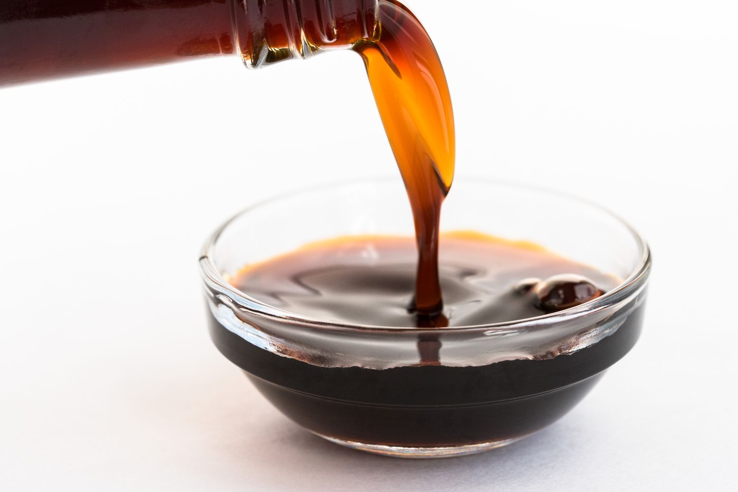Pouring coconut aminos into glass bowl
