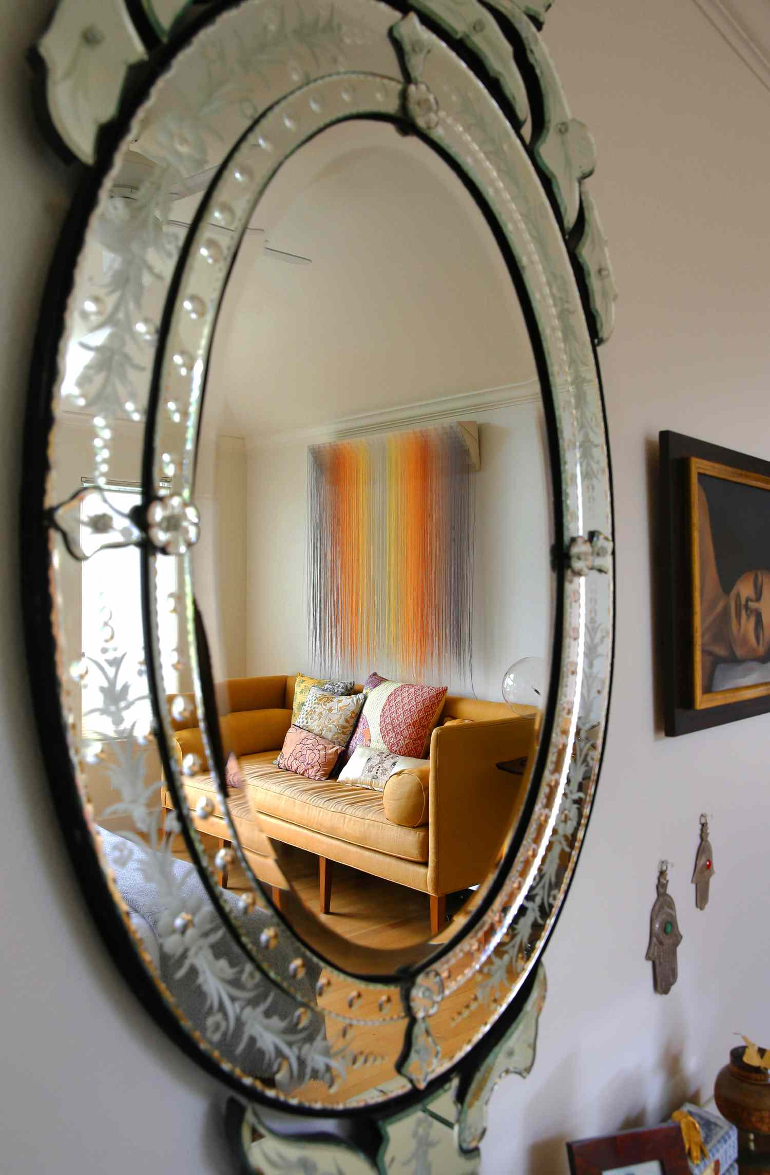 An oval mirror reflecting the interior of a room with a sofa and pillows