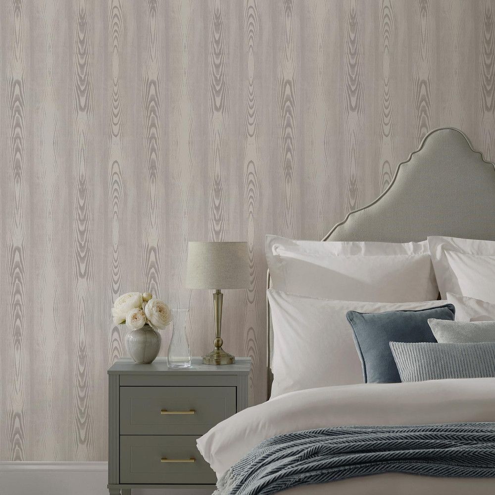 A bedroom with a bed a nightstand a lamp and faux bois wallpaper