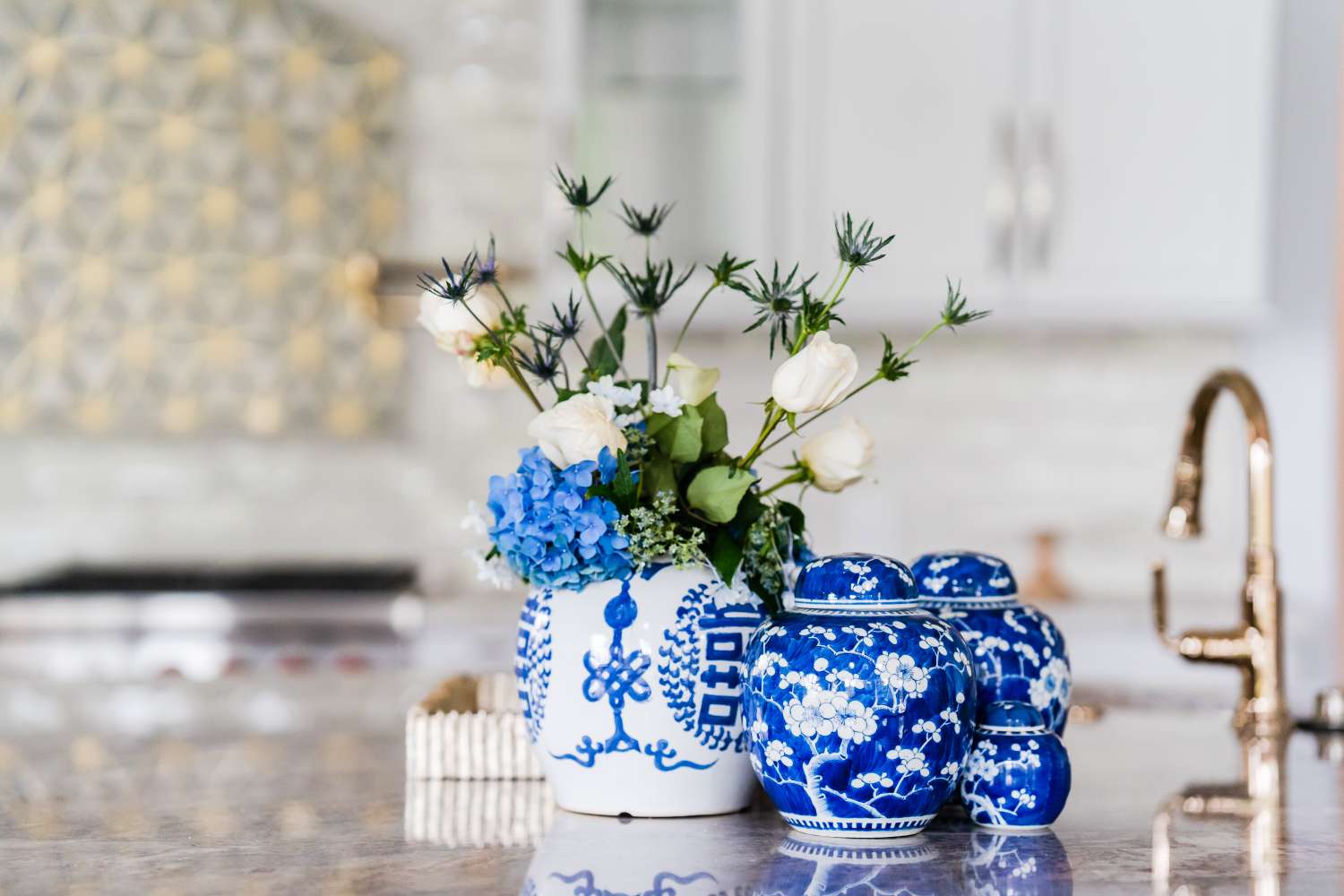 A kitchen island adorned with a floral arrangement in a decorative vase and blue and white ceramic jars