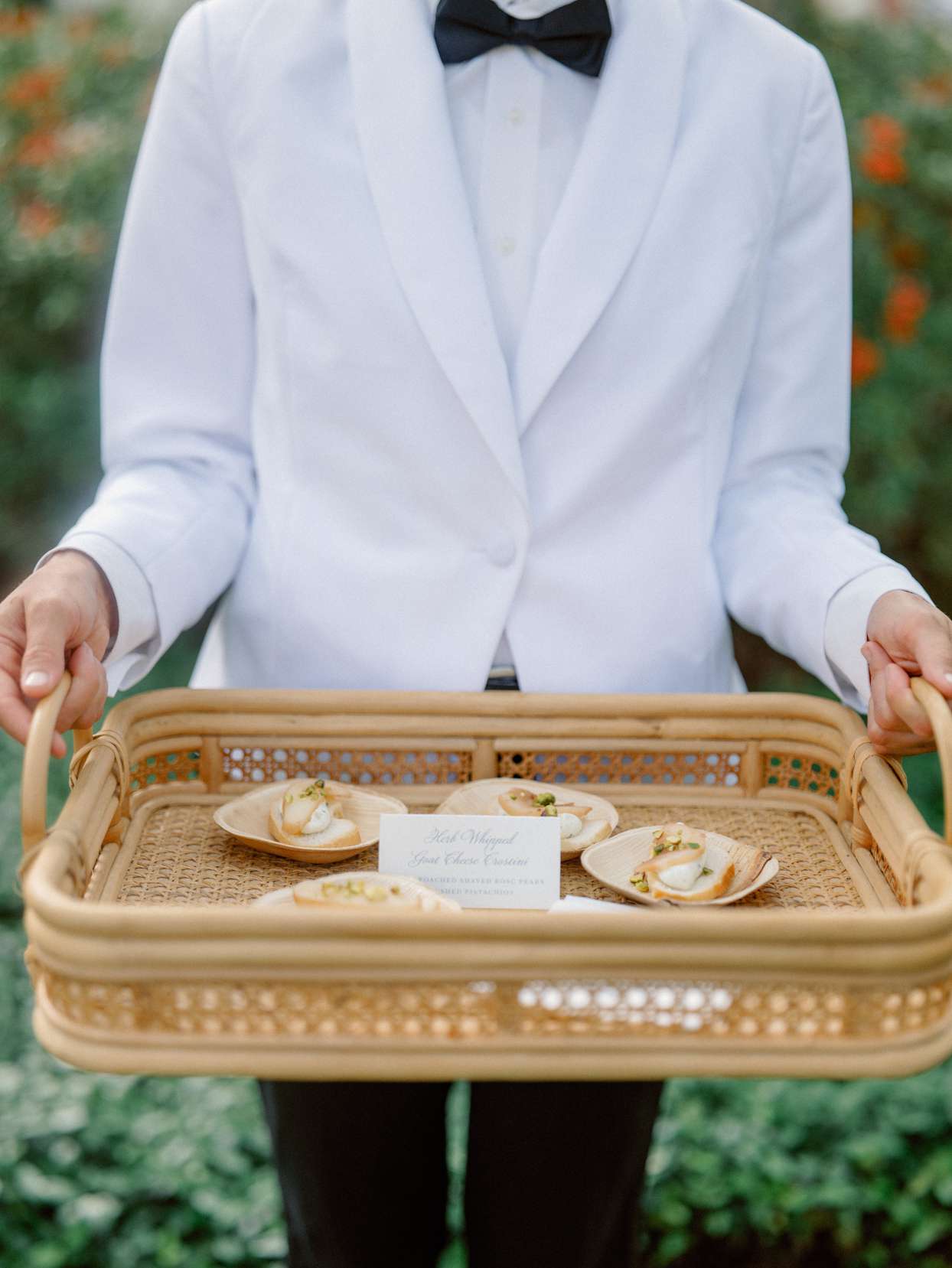 black and white tux server holding wicker serving tray with appetizers