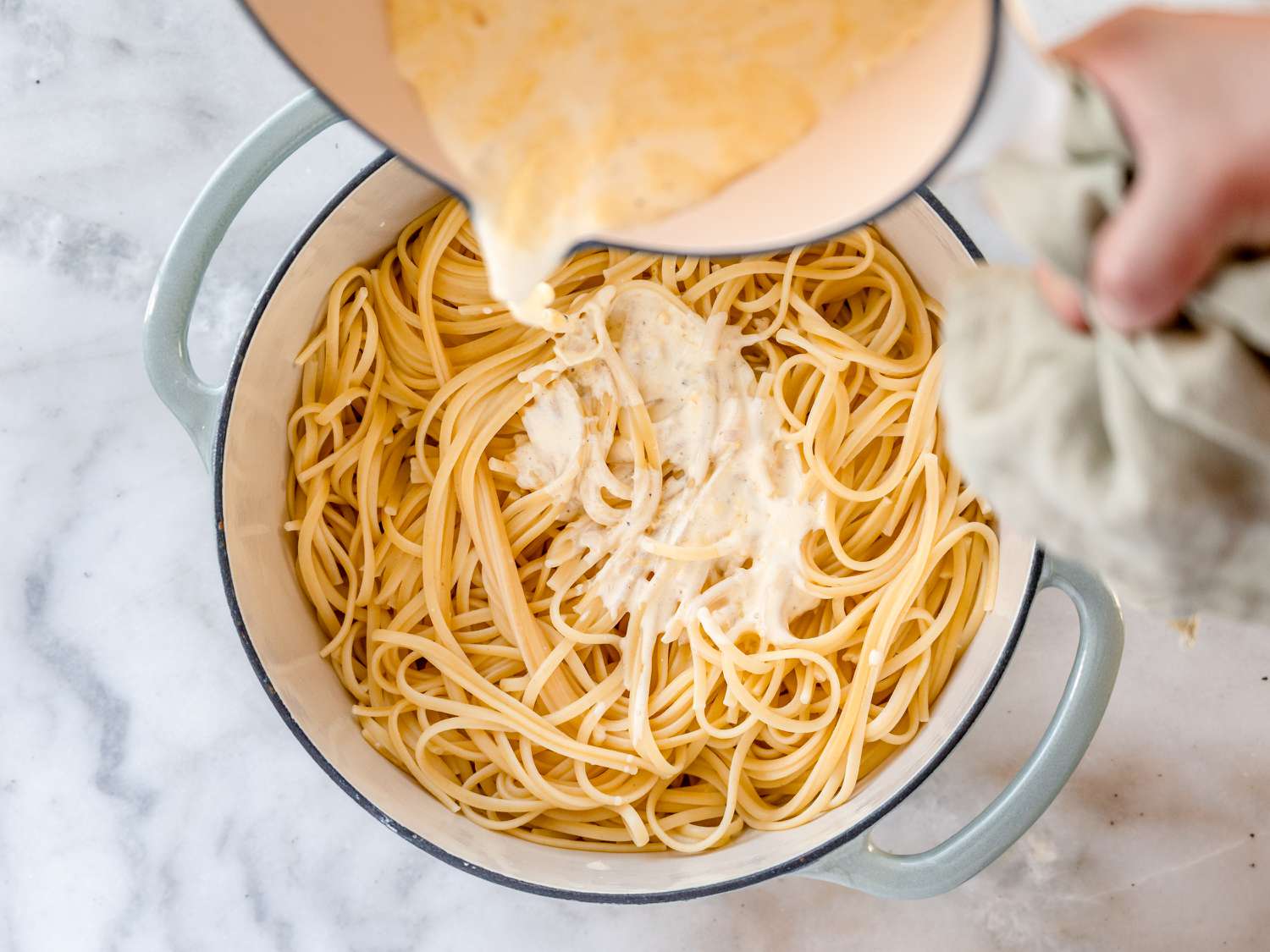 adding lemon cream sauce to linguine