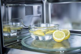 A bowl of water with lemon slices on a microwave turntable