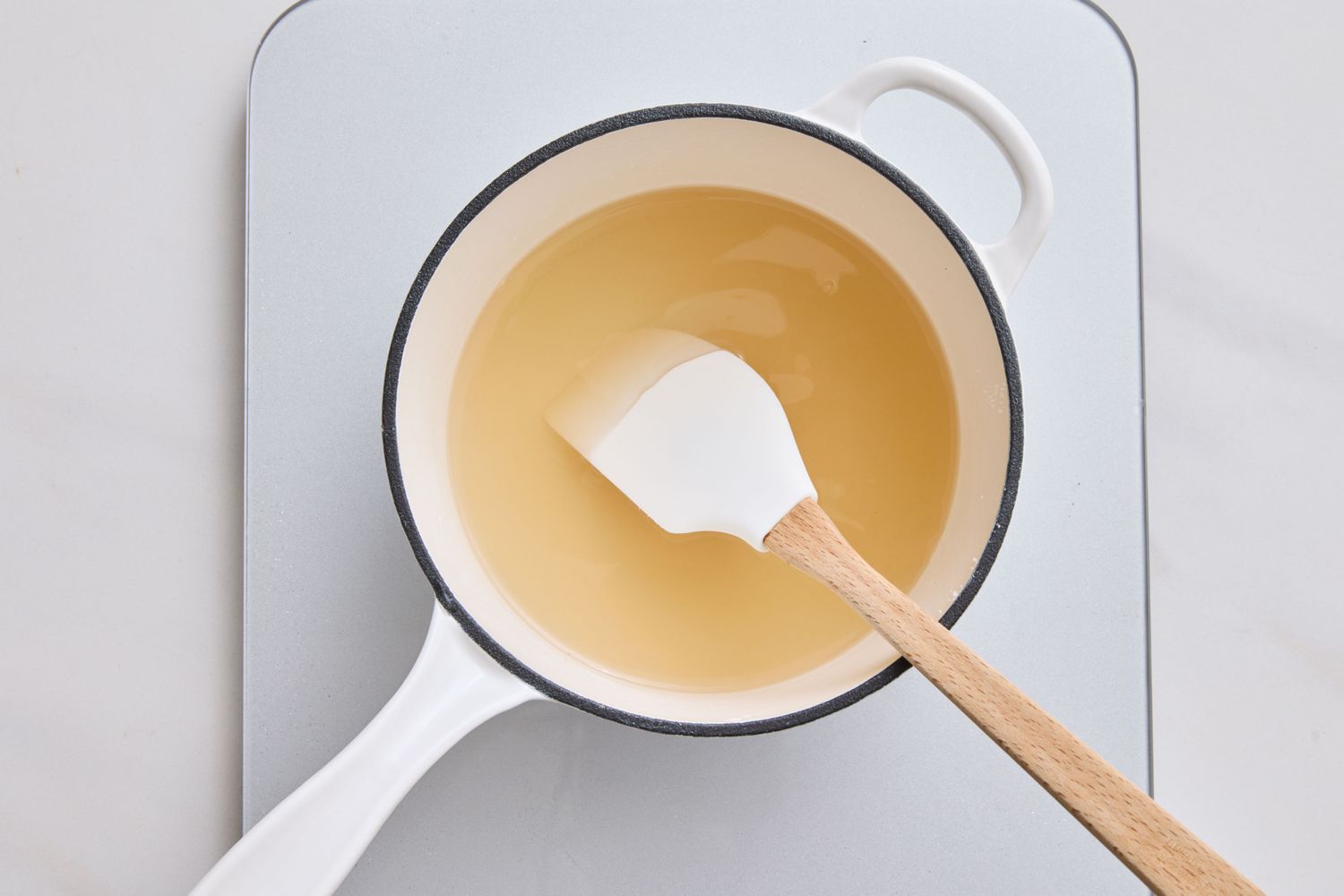 A small pot of vanillaflavored cream being stirred with a spatula