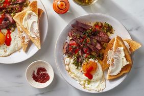 Plates with steak fried eggs toast and condiments on a table