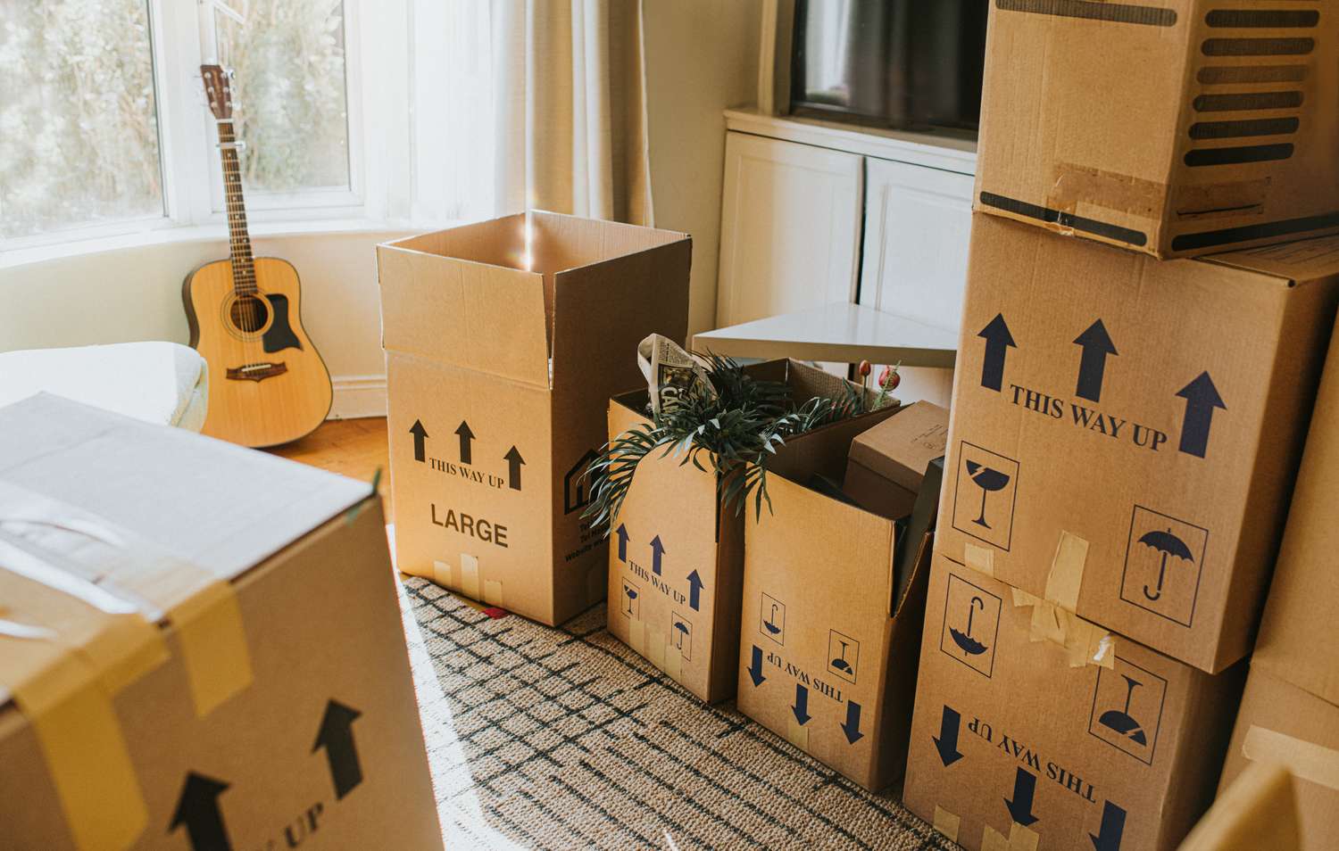 Packed moving boxes and a guitar in a room