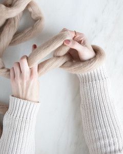 hands creating slip knot with loop around wrist for arm knit blanket