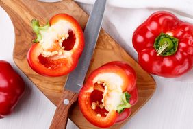 red bell pepper cut in half on cutting board with knife