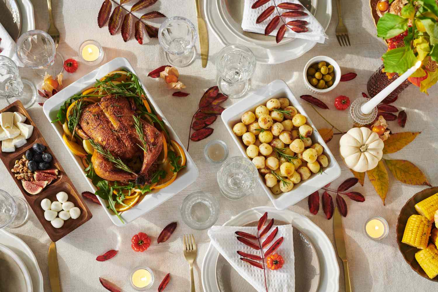 A Thanksgivingstyle meal with roasted chicken potatoes and a variety of side dishes set on a decorated table