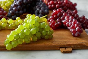 bunches of different colored grapes on a wooden board