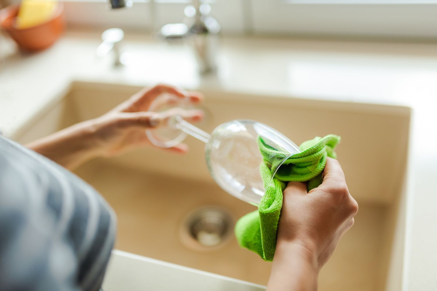 woman drying wine glass with green cloth 