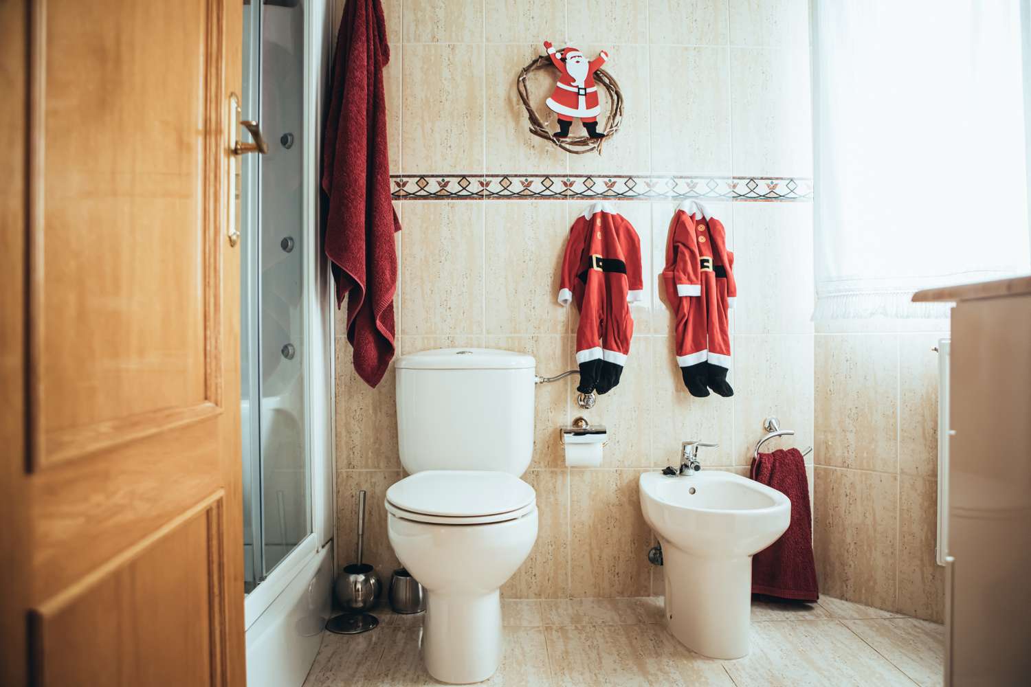 Bathroom with Santa Clausthemed decorations including small outfits hanging near toilet and bidet