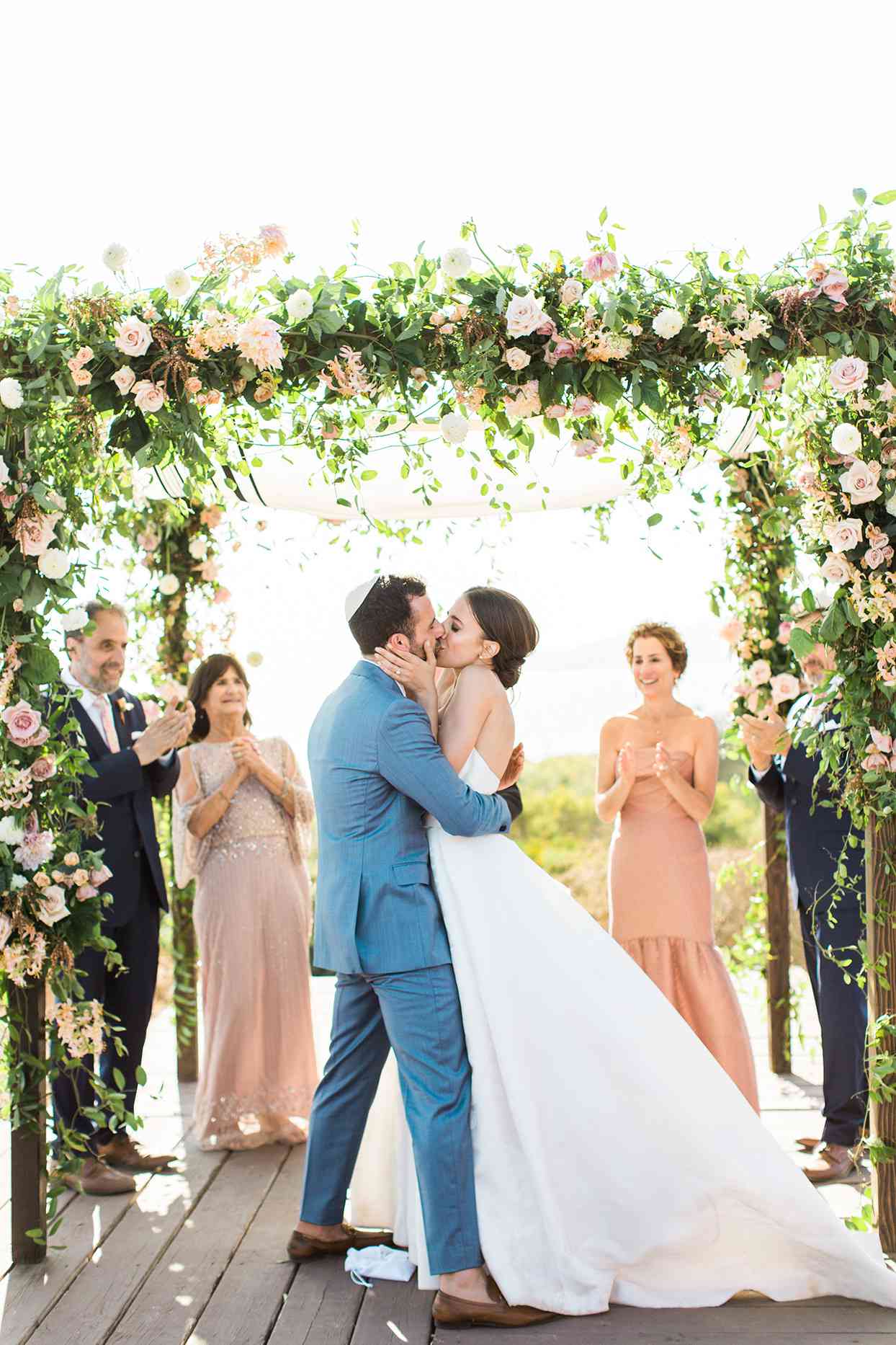 wedding couple kiss under chuppah in jewish ceremony