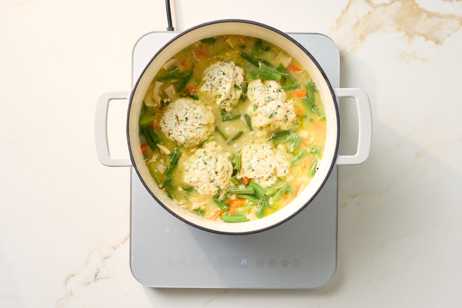 A pot of chicken and dumplings cooking on a stovetop