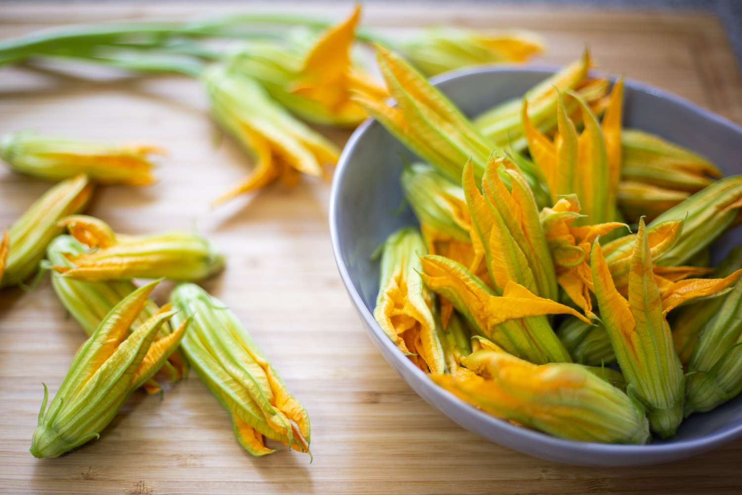 squash blossoms in a bowl and on bamboo surface