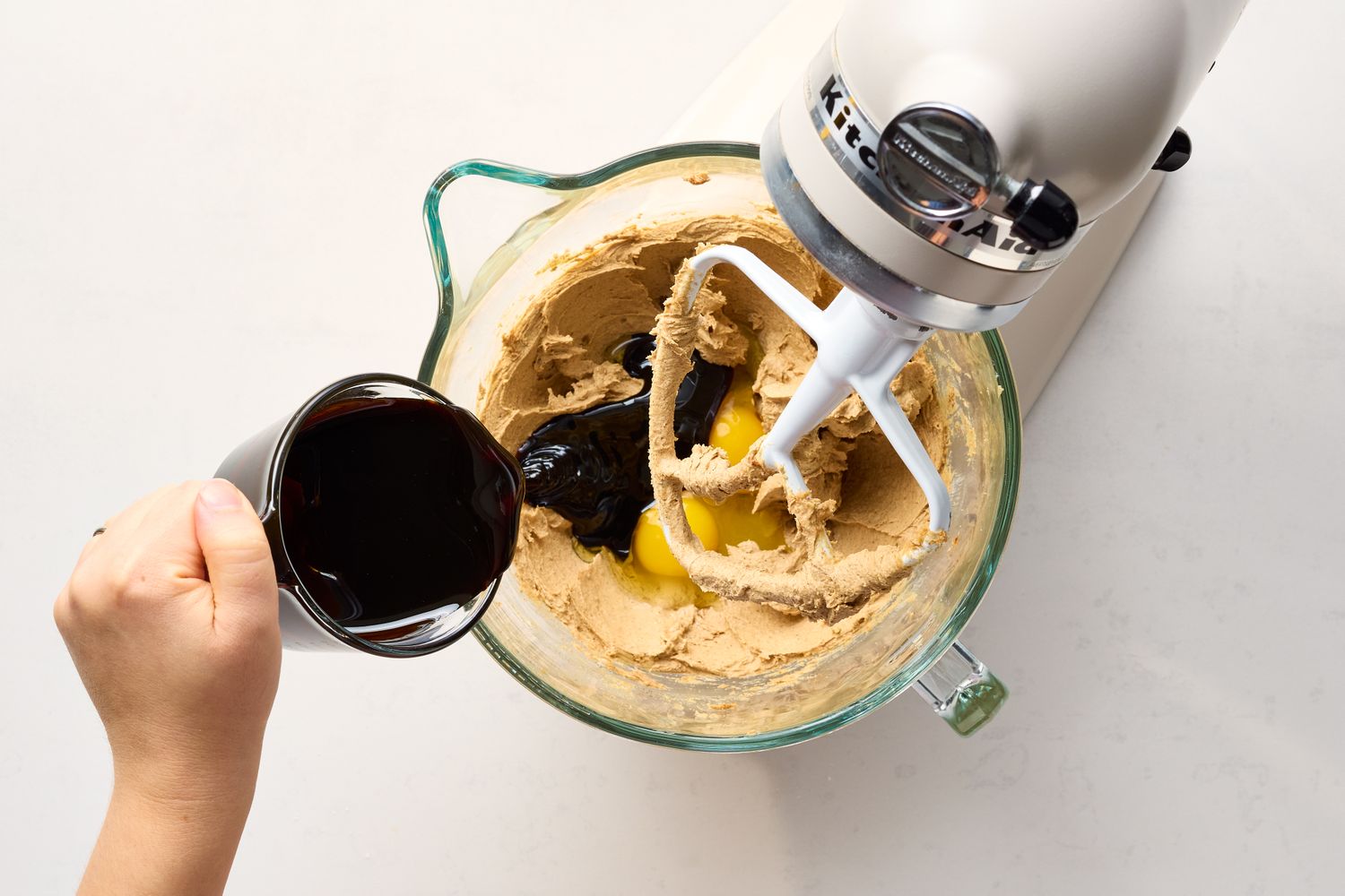 Adding liquid ingredients to a stand mixer with cookie dough mixture