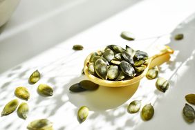 pumpkin seeds in a large spoon on a white background
