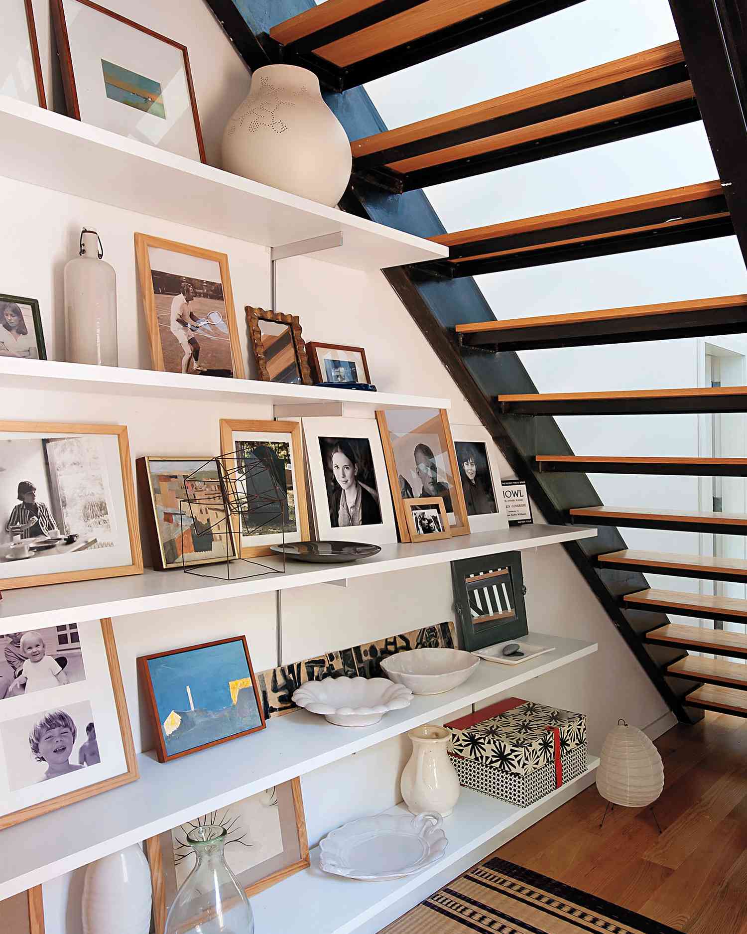 A staircase with shelves and frames underneath 
