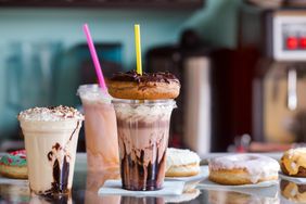 milkshakes in plastic cups with straws and various donuts