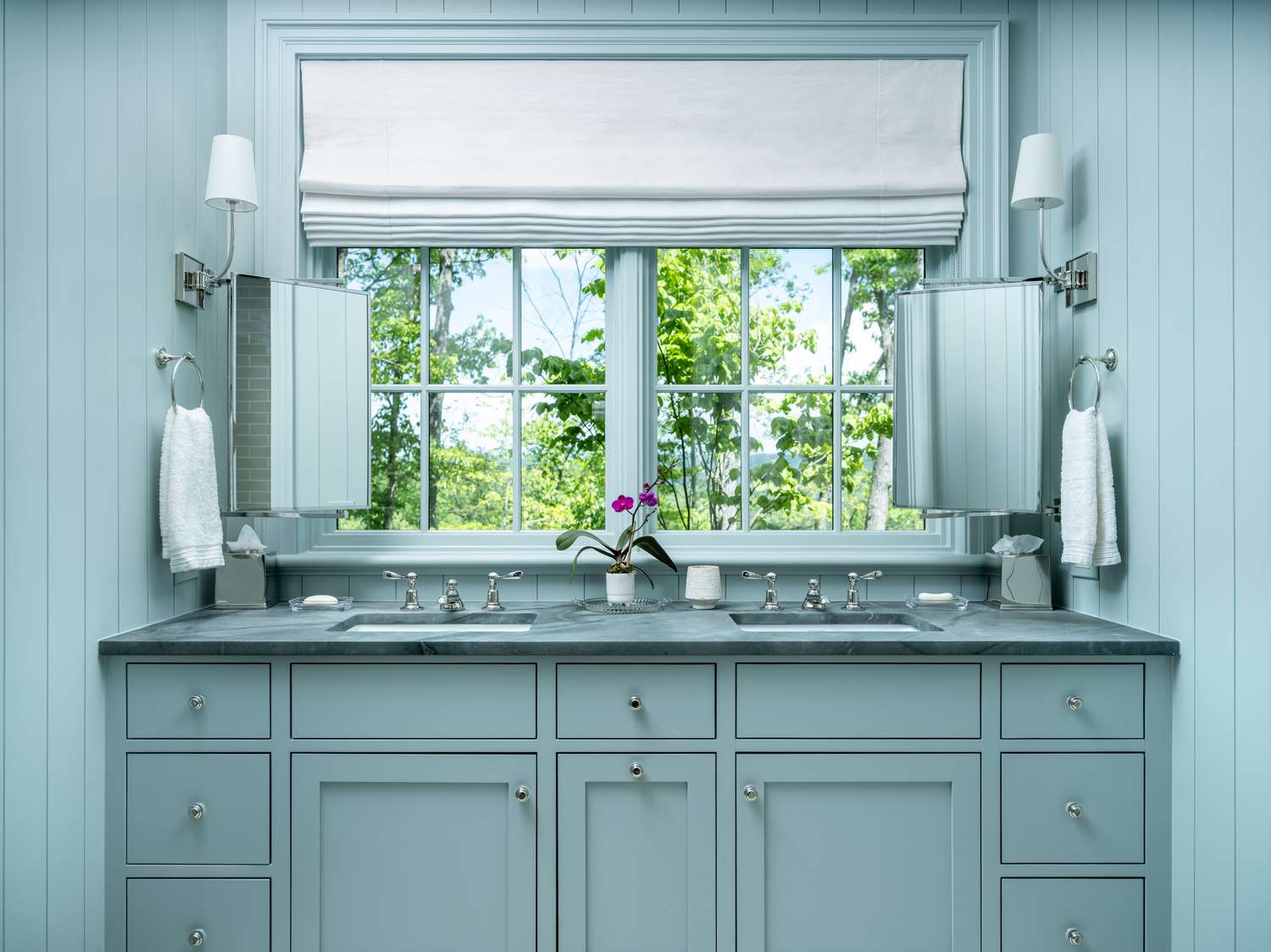 a blue bathroom with small mirrors 