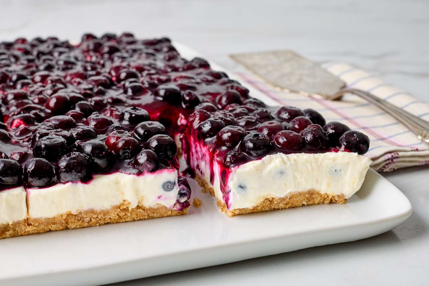 Blueberry cheesecake with a cut piece on a serving platter