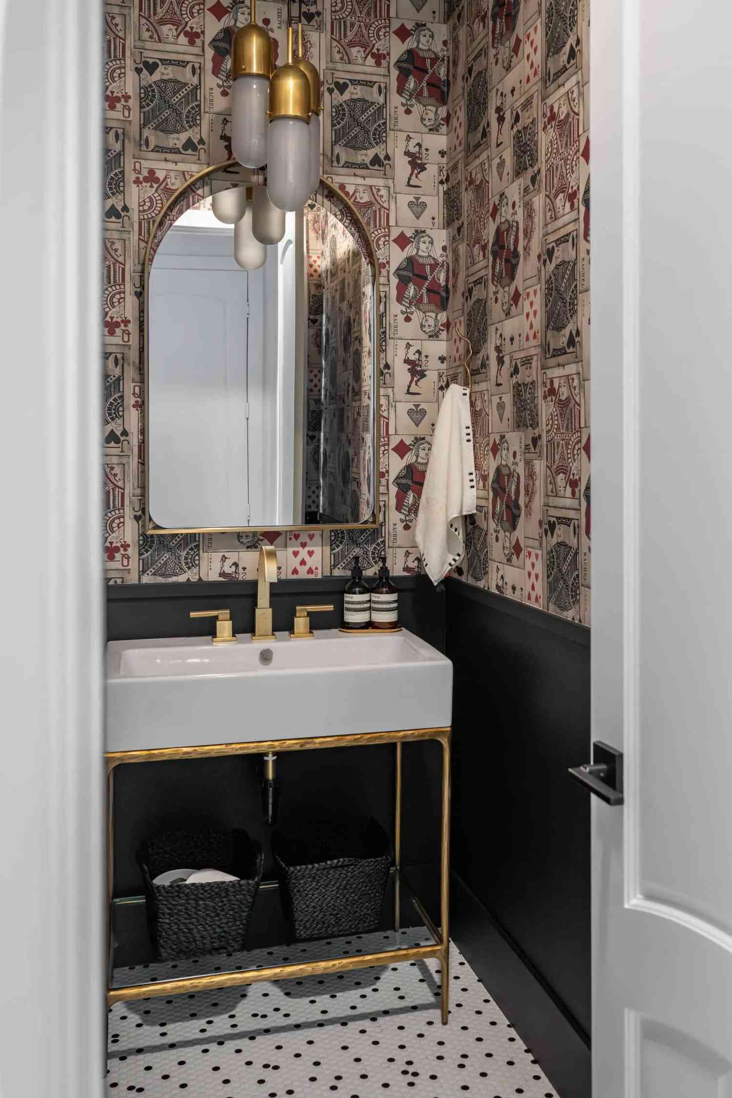 a powder bathroom with a wallpaper that contains playing cards
