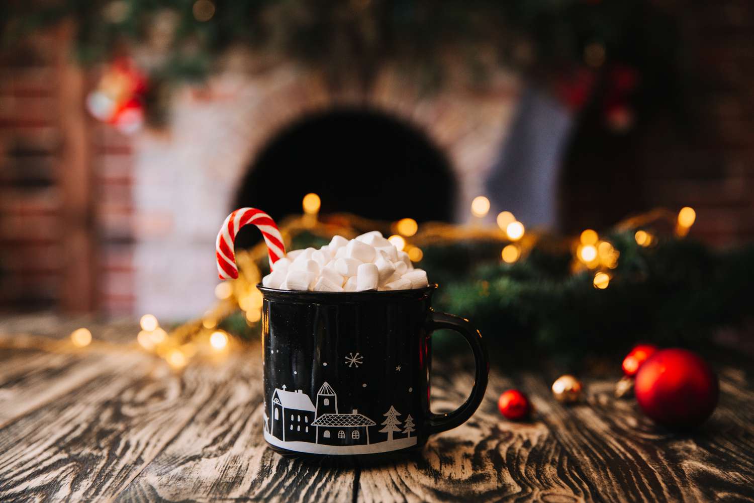 christmas mug with coffee or tea on a wooden table against the background of a burning fireplace