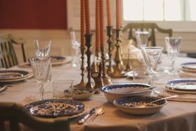A dining table set with plates glasses utensils and candles