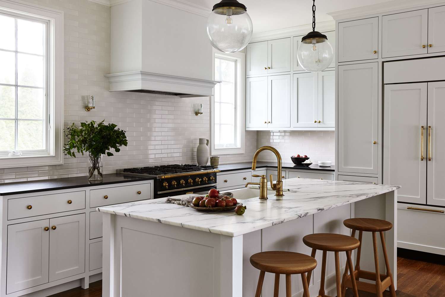 Kitchen interior with white cabinetry, marble island counter, and wooden stools