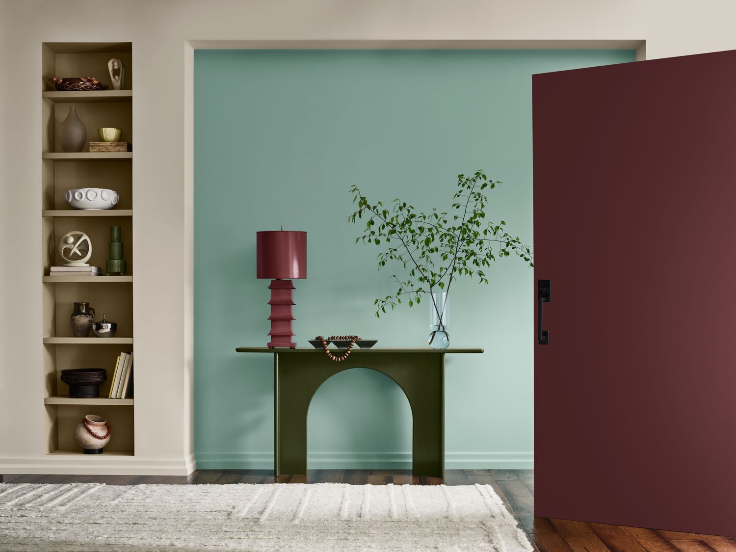 An interior entryway featuring a green table with decorative items a shelf with objects and a door partially open