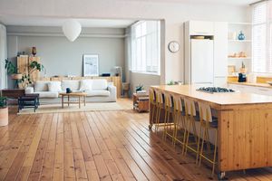 Modern openplan living area with wooden flooring a cozy sofa and a kitchen island with chairs