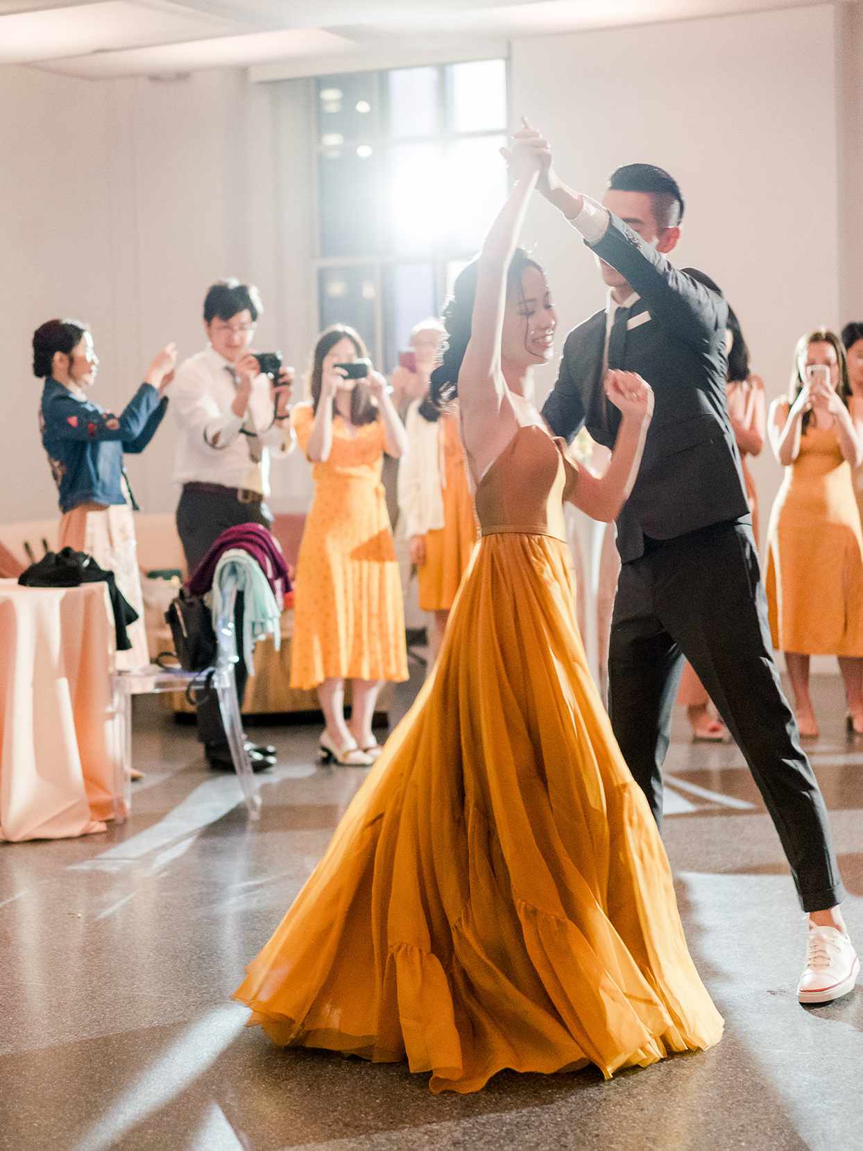 bride in yellow and groom twirling for wedding first dance