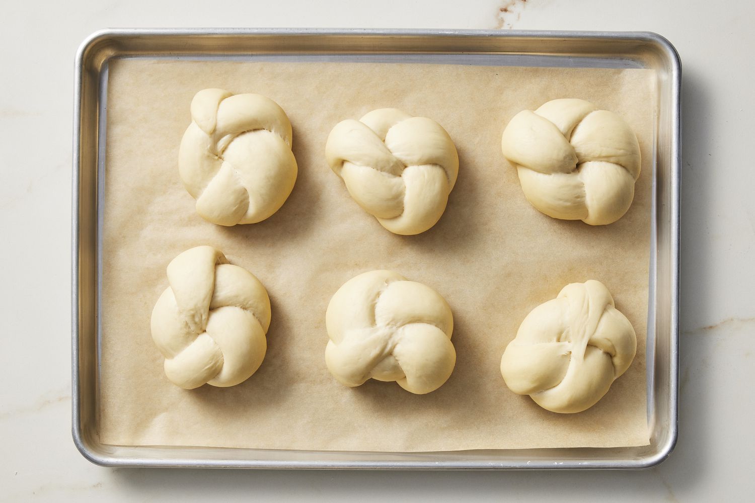 Risen dough knots on baking sheet
