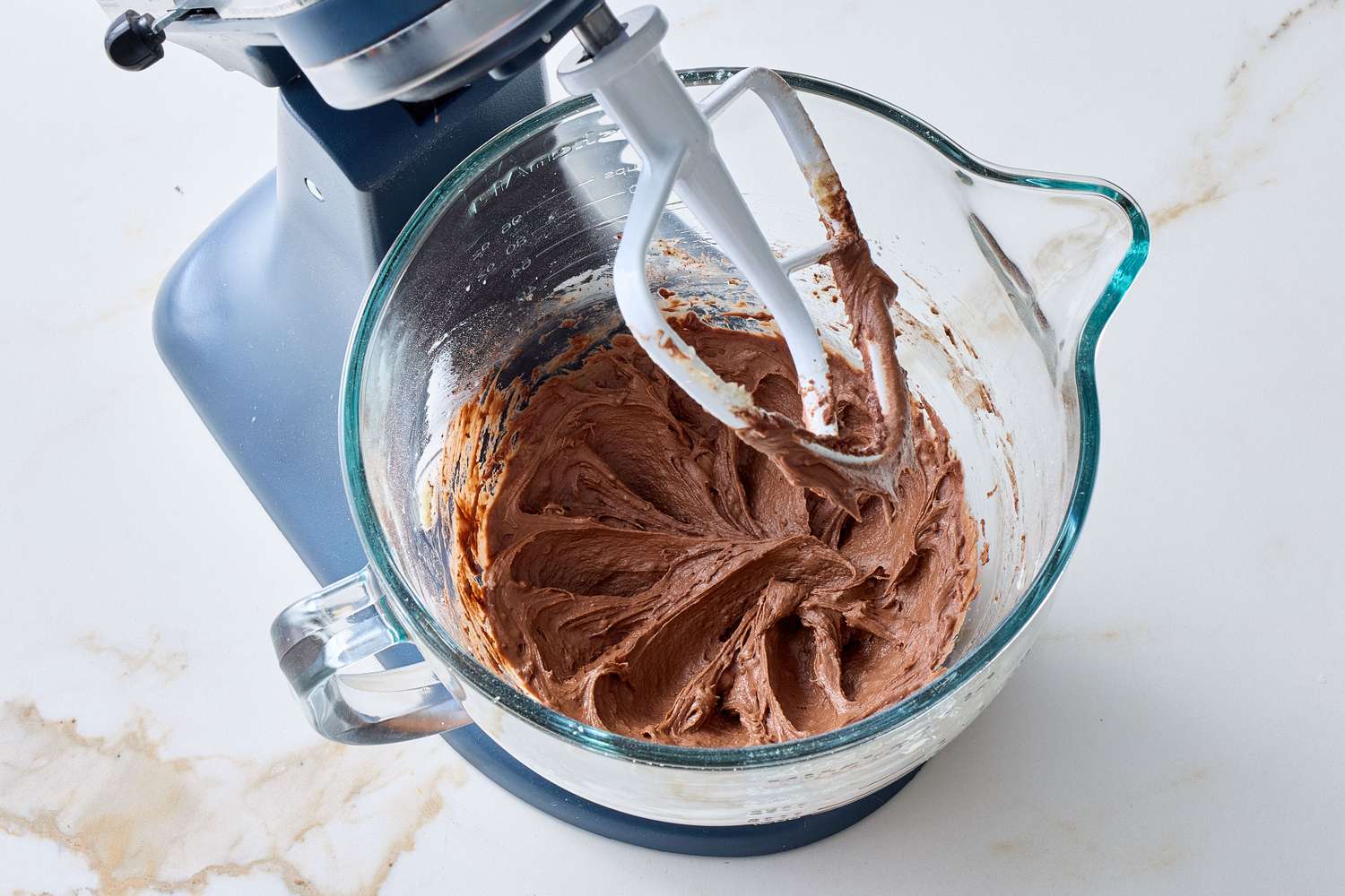 Stand mixer mixing chocolate batter in a glass bowl