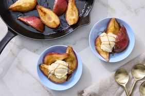 Caramelized pears served in a skillet and plated with ice cream on blue dishes