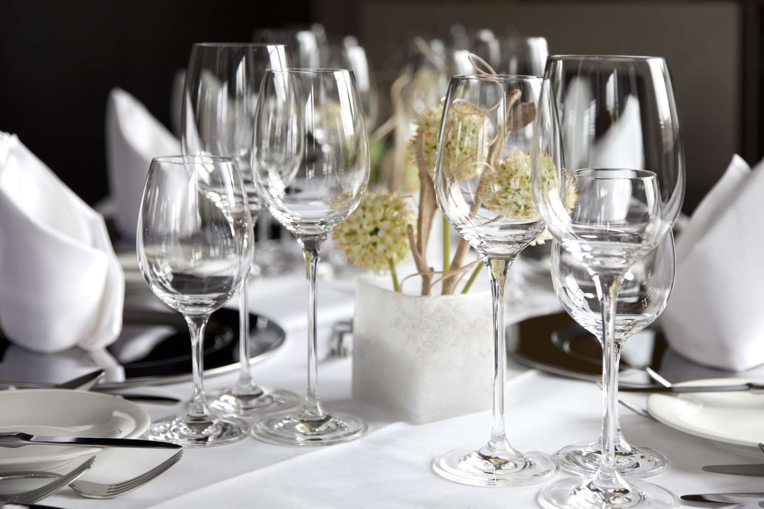 Elegant dining table setup with wine glasses and a small floral centerpiece