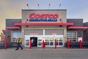 Exterior shot of a Costco Wholesale store at dusk with Costco Wholesale signage and people entering, exiting.