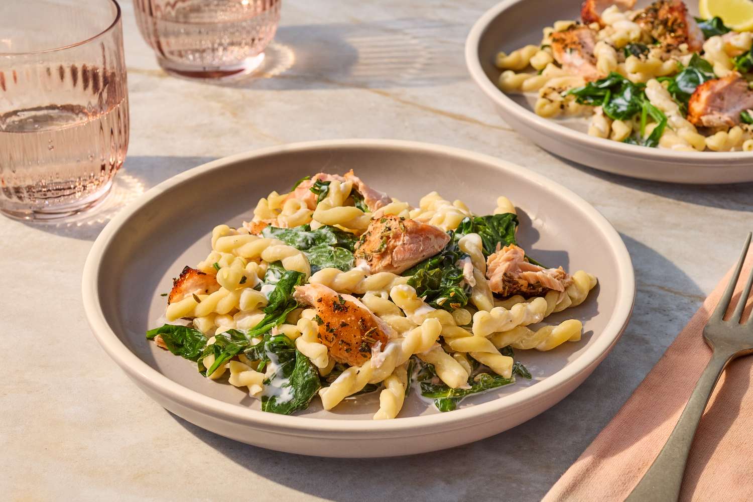 A plate of pasta with salmon spinach and cream sauce