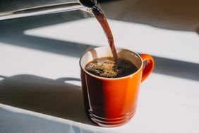 Coffee being poured into orange mug