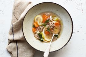 A bowl of quinoa vegetable soup with a spoon on a table