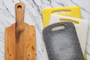 Side by side view of wooden and plastic cutting boards. Concept of kitchen choice, hygiene, food safety, sustainability, and household preferences