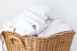 clean white sheets and towels in basket