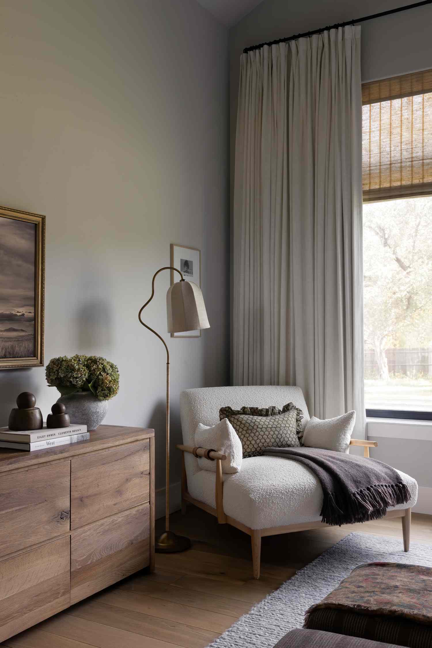 A cozy sitting area with an armchair floor lamp and wooden dresser