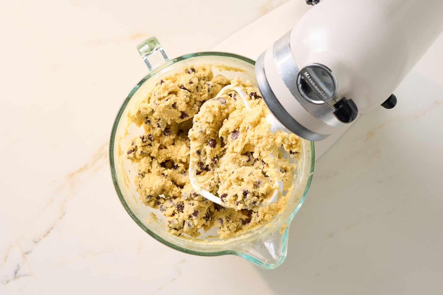 Stand mixer and a bowl filled with cookie dough with chocolate chips