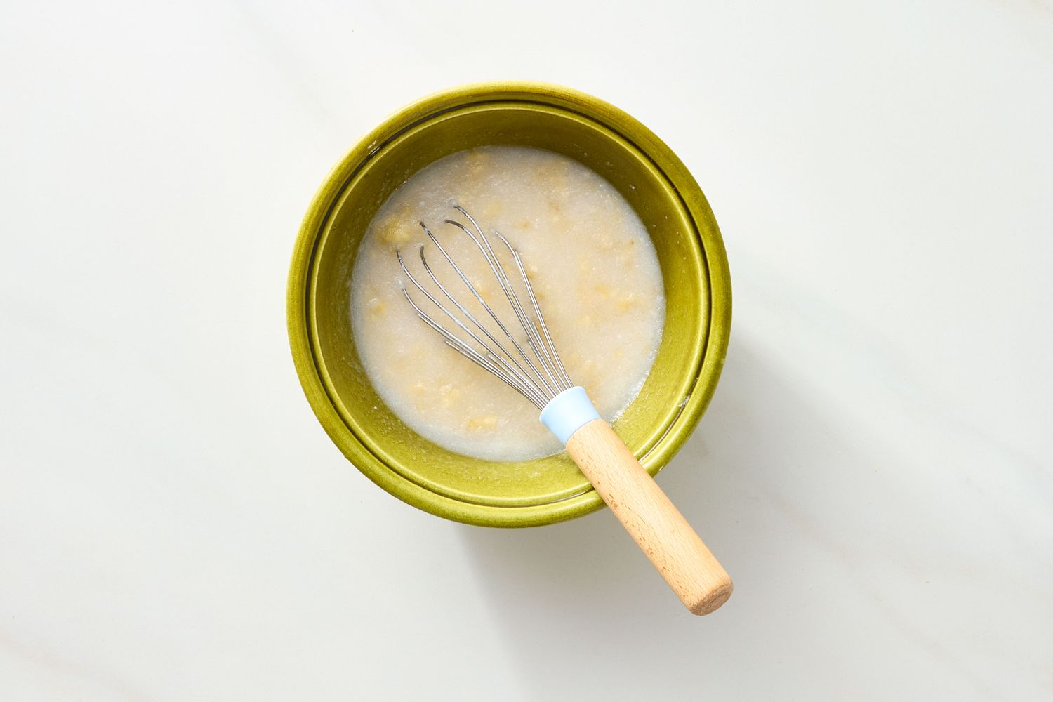 A bowl with a whisk stirring a liquid mixture likely for baking
