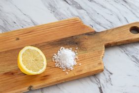 Wooden cutting board with half a lemon and coarse salt used for cleaning
