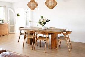 A dining room setup with a wooden table chairs and decorative light fixtures hanging above