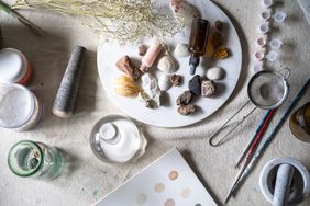A creative workspace with art supplies, shells, natural objects and tools arranged on a table