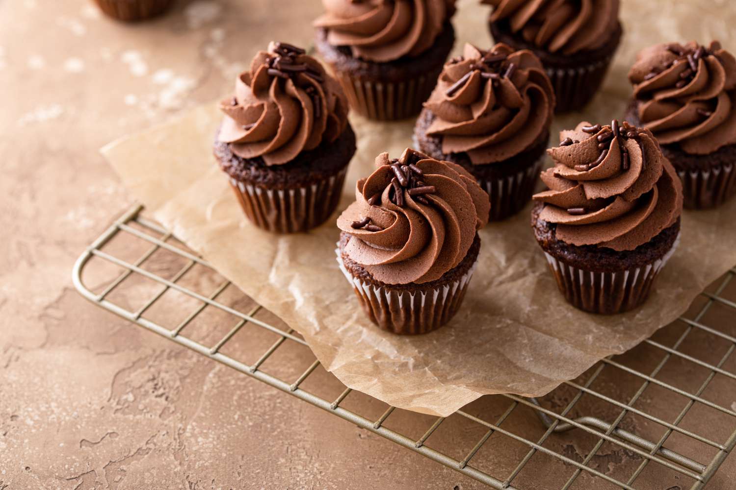 chocolate cupcakes with chocolate frosting on cooling rack